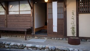 A traditional Japanese building with a wooden exterior, a stone pathway, and a potted plant. - UCHIKO-Inn HISA (Uchiko)