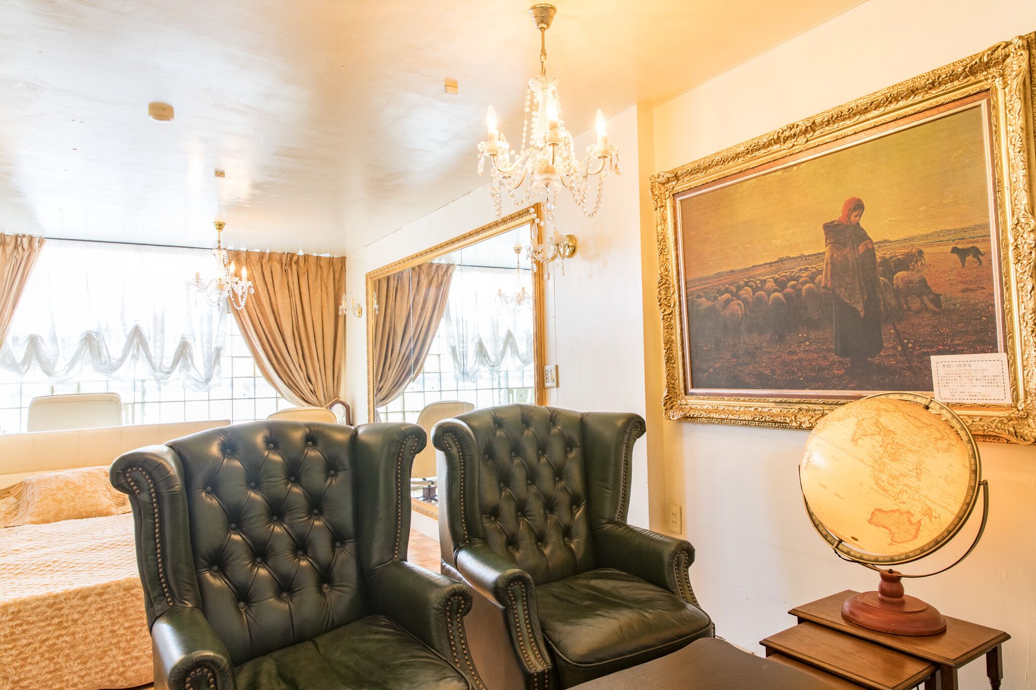 Um quarto com duas poltronas de couro, um candelabro, um globo terrestre e um quadro emoldurado na parede.