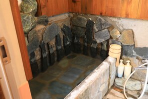 A stone hot tub with wooden walls and a wooden bucket. - Atami Japan Onsen House (Atami)
