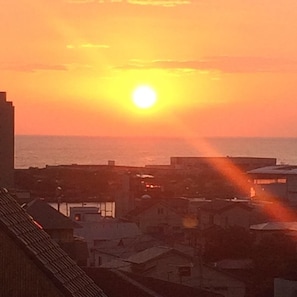 Een zonsondergang boven een kustplaats met gebouwen en de zee.