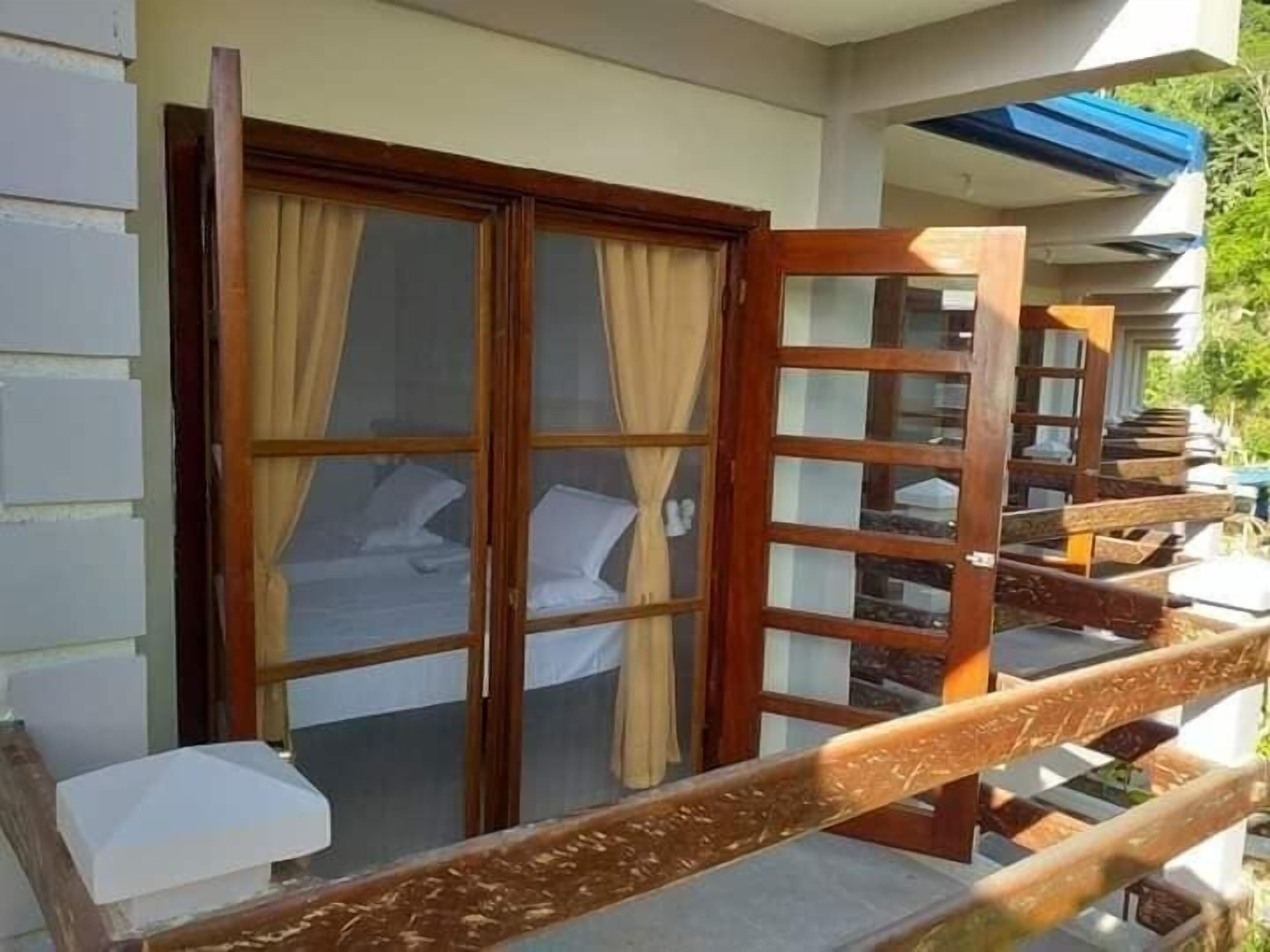 A hotel room with a large sliding door, a bed, and a view of the outdoors.