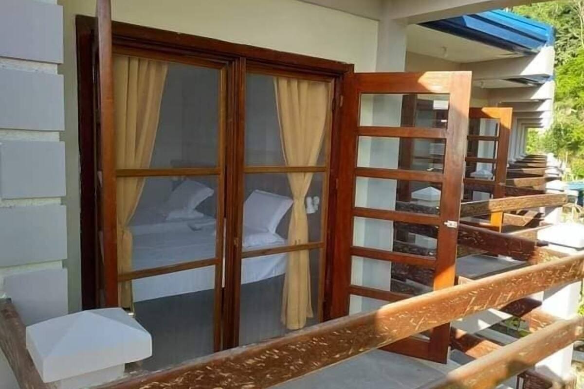 A hotel room with a large sliding door, a bed, and a view of the outdoors.