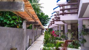 A corridor with a wooden staircase, concrete walls, and balconies with railings. - Ferellee Beachfront Inn (San Vicente)