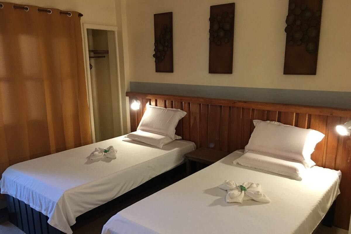 Two single beds with white linens, wooden headboards, and a wooden wall panel.