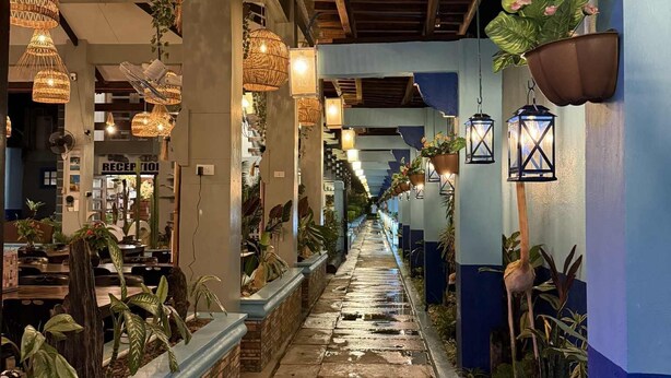 A corridor with hanging wicker lamps, potted plants, and a reception area. - Ferellee Beachfront Inn (San Vicente)