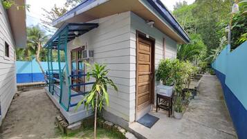 Una casa pequeña de un piso con una puerta de madera y una ventana con marco azul.