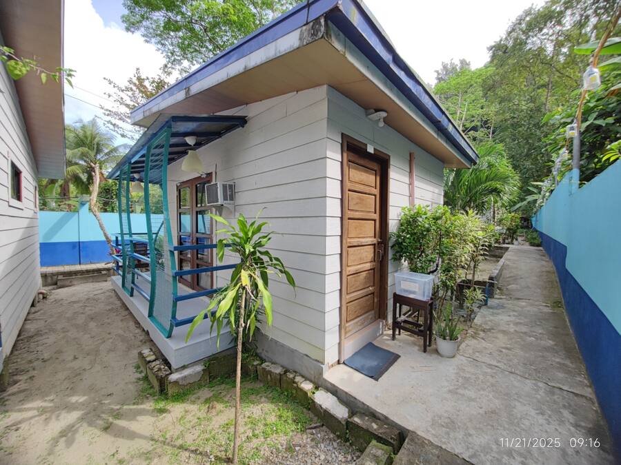 Una casa pequeña de un piso con una puerta de madera y una ventana con marco azul.