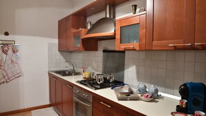 A kitchen with wooden cabinets, a stainless steel stove, and a coffee maker. - Agriturismo Memento (Follina)