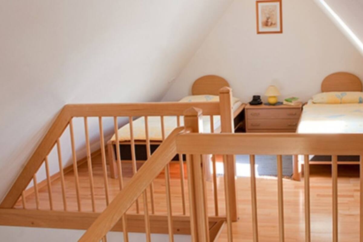 A bedroom with a wooden bunk bed, a bedside table with a lamp, and a framed picture on the wall.
