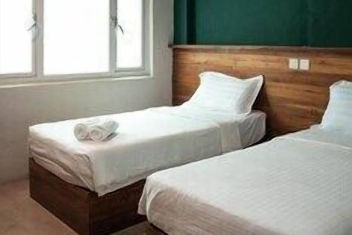 A room with two beds, a window, and a ceiling fan.