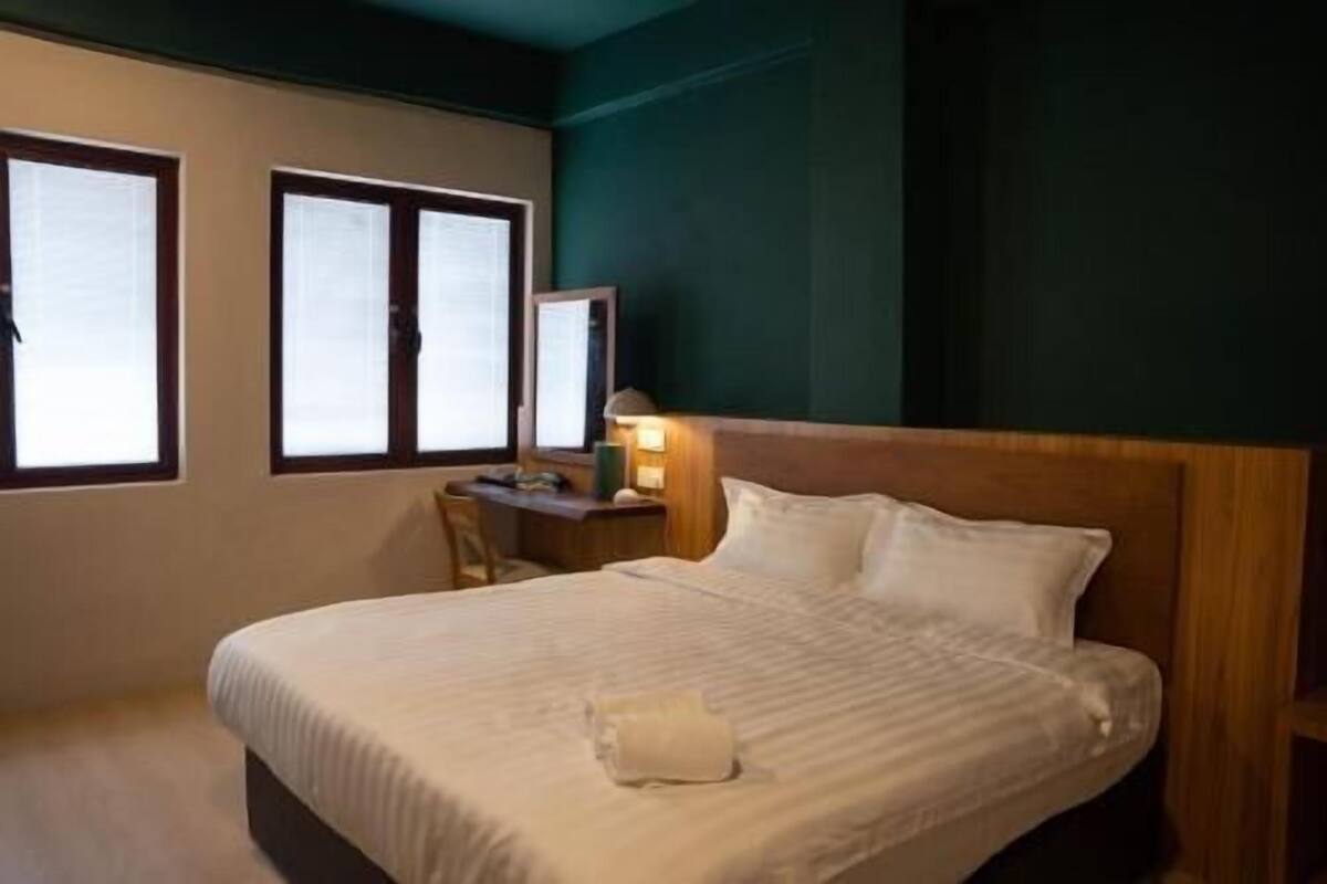 A hotel room with a bed, a desk, and a chair.