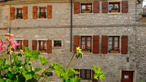 A stone building with multiple windows, some with shutters, and flower boxes on the windowsills. - Agriturismo Crodi (Miane)