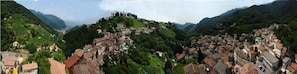 A mountainous village with terraced vineyards, historic buildings, and a prominent church on a hilltop. - Agriturismo Crodi (Miane)