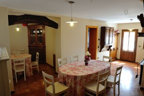 A dining area with a round table and chairs, a wooden cabinet, and a hanging light fixture. - Agriturismo Crodi (Miane)