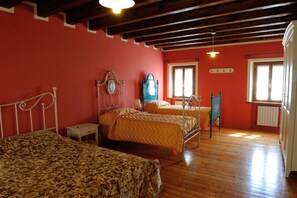 A bedroom with two beds, wooden flooring, and a red wall. - Agriturismo Crodi (Miane)