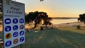 Un panneau indiquant les commodités disponibles et offrant une vue sur la plage de La Colada au coucher du soleil.
