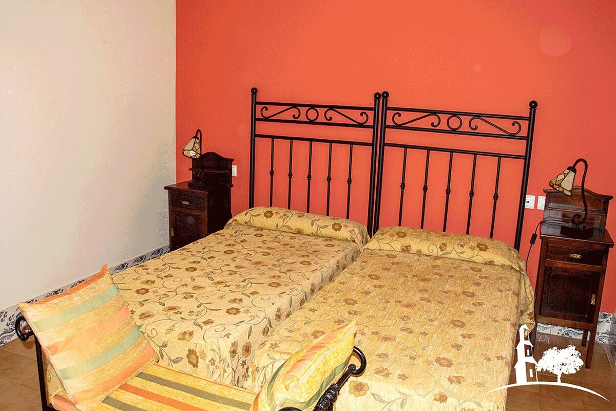 Ein Doppelbett mit floralem Bettzeug, zwei Nachttische mit Lampen und eine rote Wand.