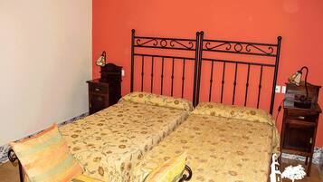 Un llit doble amb roba de llit floral, dues taules de nit amb làmpades i una paret vermella.