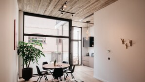 Un comedor moderno con un amplio ventanal, una planta en maceta y una mesa con revistas.