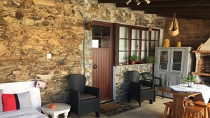 Una habitación rústica con paredes de piedra, muebles de mimbre, una puerta de madera y un horno de ladrillo.