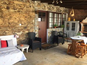 Una habitación rústica con paredes de piedra, muebles de mimbre, una puerta de madera y un horno de ladrillo.
