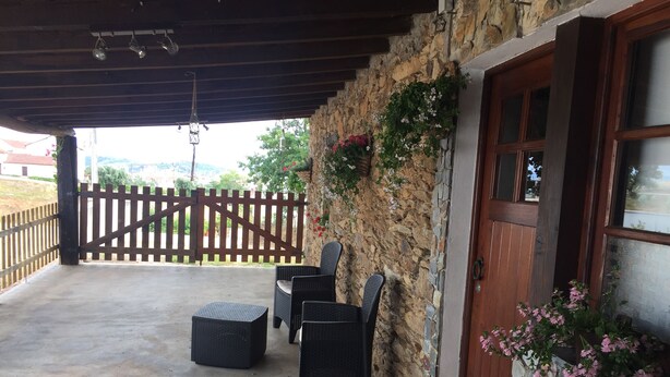 Un patio techado con mobiliario de mimbre y una pared de piedra.