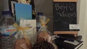 Una mesa con agua embotellada, pan, piñas y una pizarra con la inscripción 'Bem Vindos'.