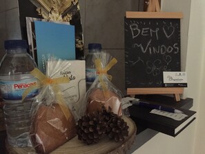 Una mesa con agua embotellada, pan, piñas y una pizarra con la inscripción 'Bem Vindos'.