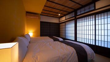 Une pièce de style japonais traditionnel, avec un sol recouvert de tatamis, un plafond bas avec des poutres en bois et des panneaux coulissants en papier.