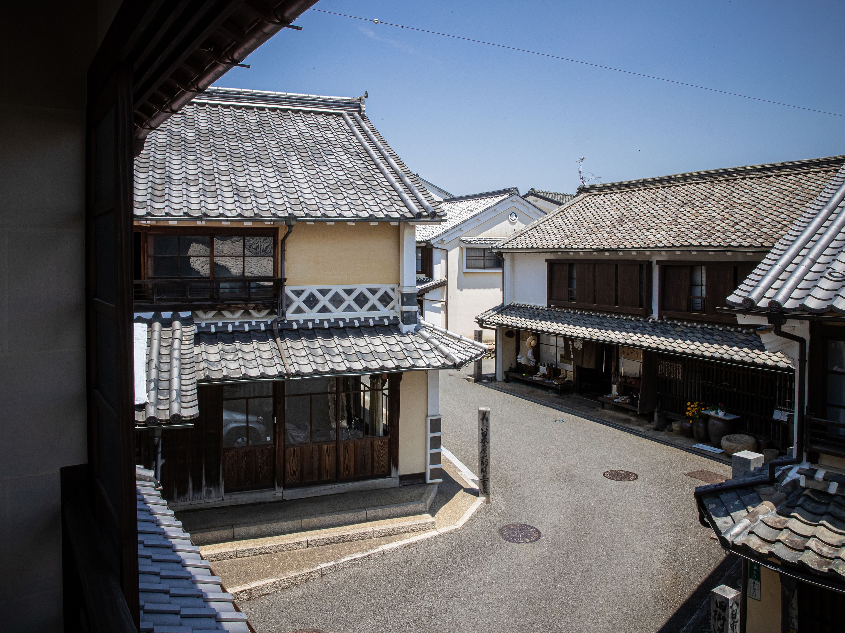 A traditional Japanese street with buildings featuring tiled roofs and wooden structures.