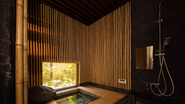 A modern bathroom with a wooden bathtub, bamboo wall panels, and a built-in shower. - UCHIKO-Inn ORI (Uchiko)