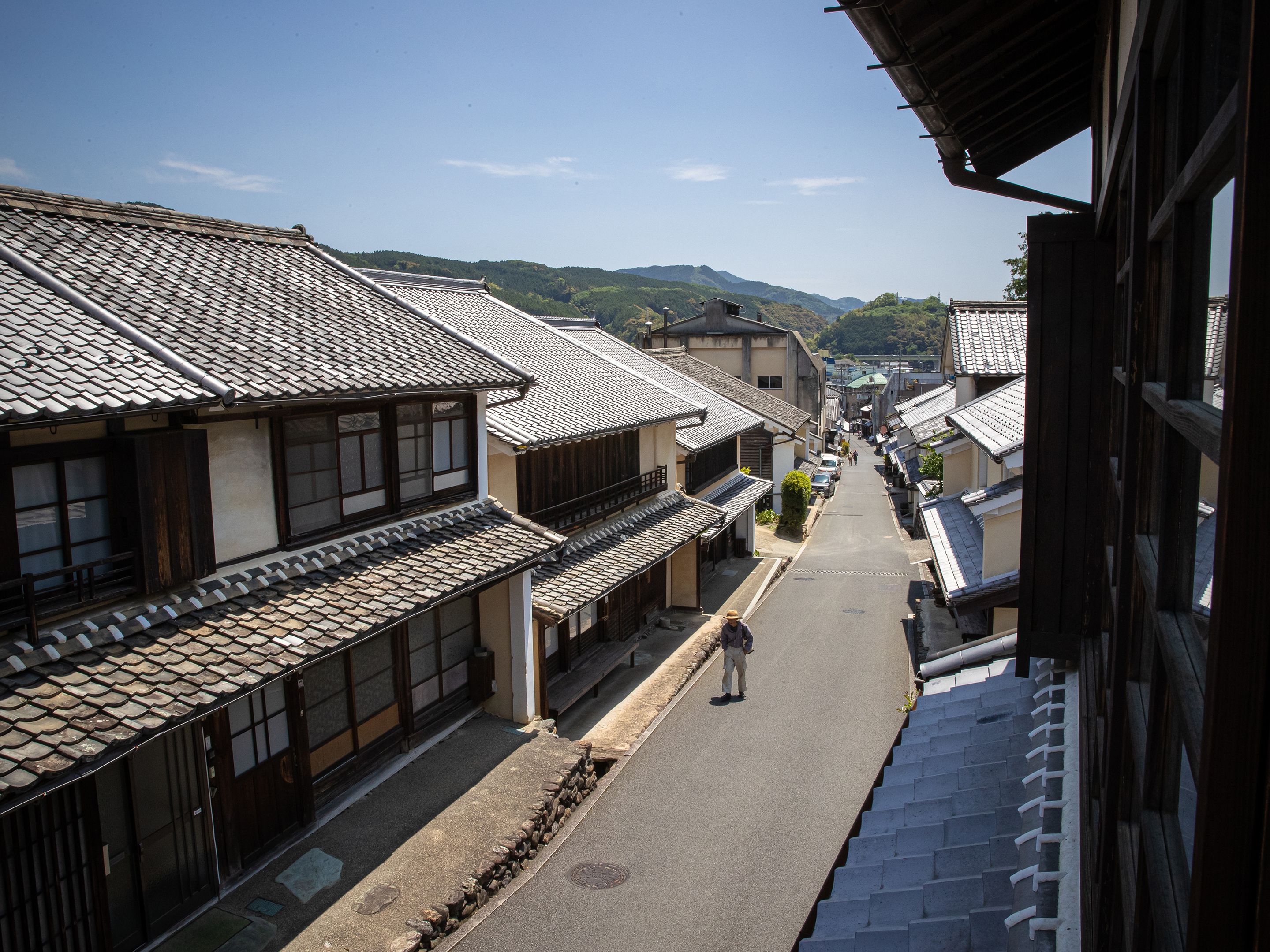A traditional Japanese street with buildings featuring tiled roofs and wooden structures.