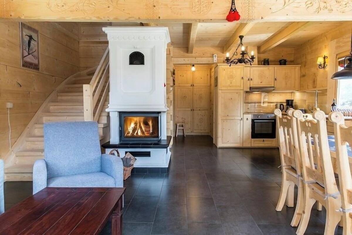 A wooden interior with a fireplace, a staircase, a dining area, and a kitchen.