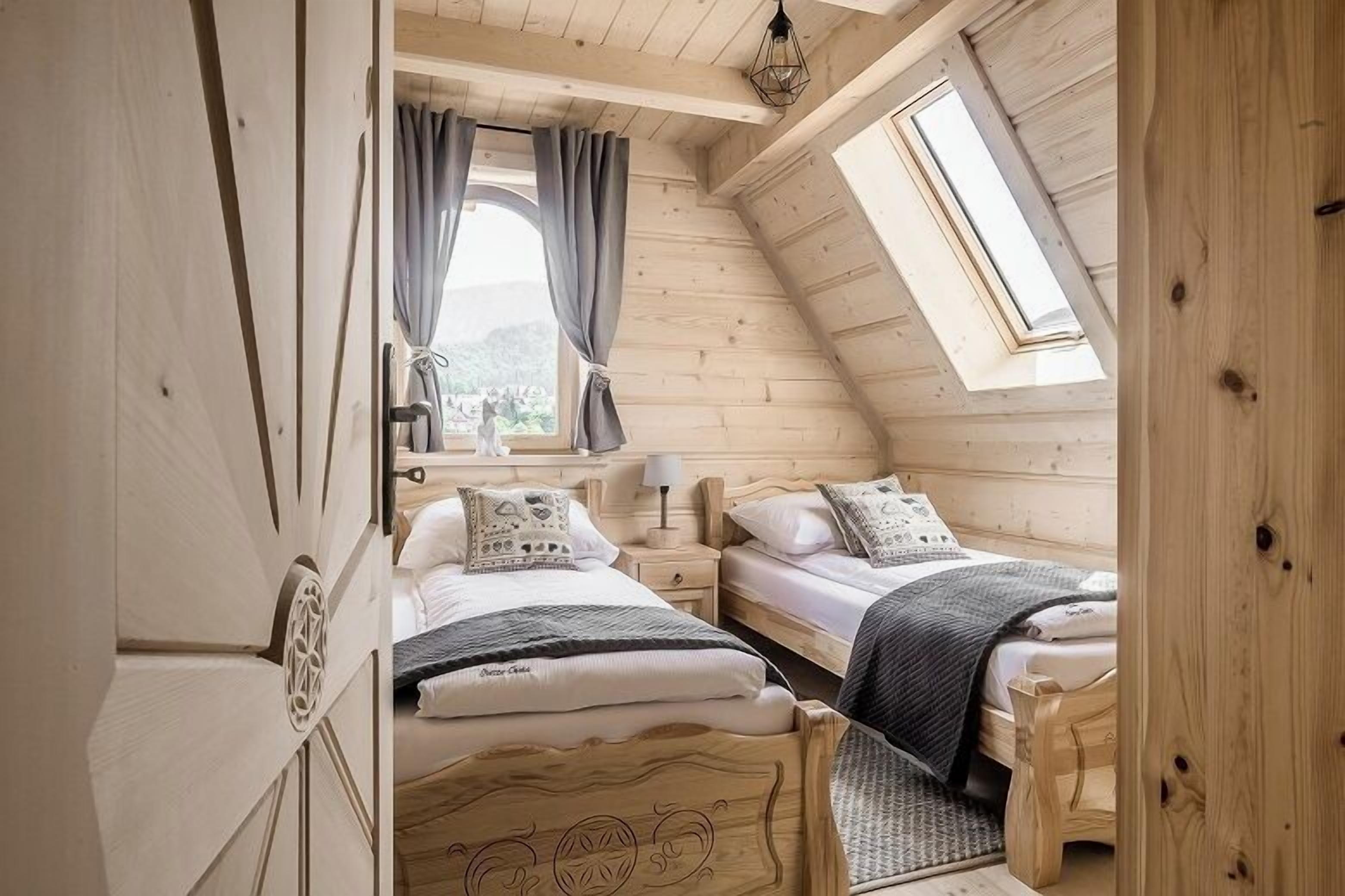 Een gezellig slaapkamer op zolder met twee houten bedden, een dakraam en uitzicht op de omgeving.