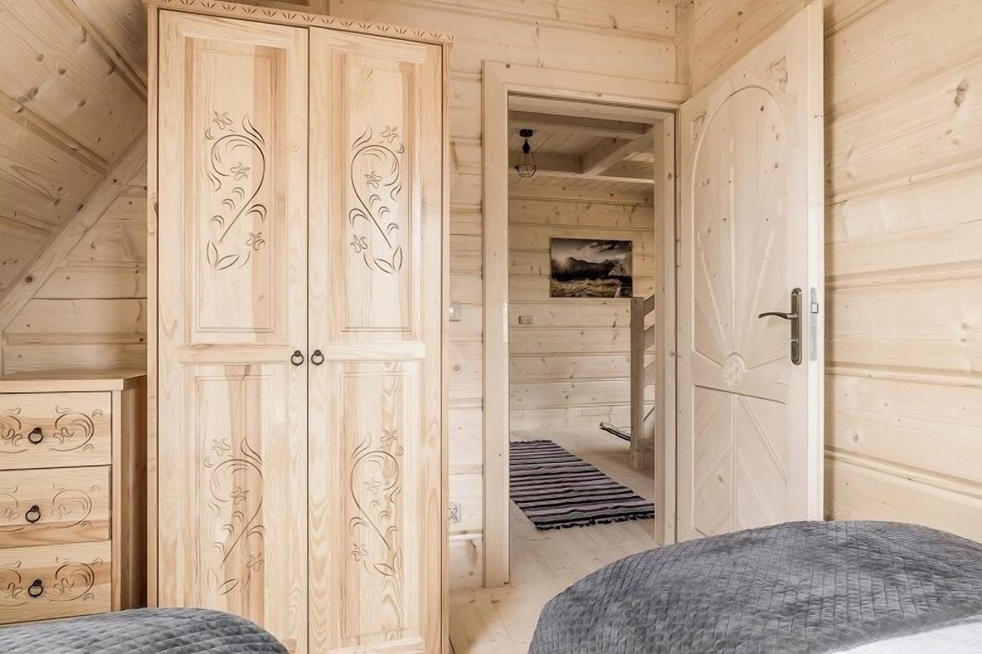 Una habitación de madera con una cama, un armario y una puerta que da a otra habitación.