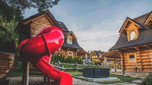 A log cabin-style building with a playground featuring a red slide.