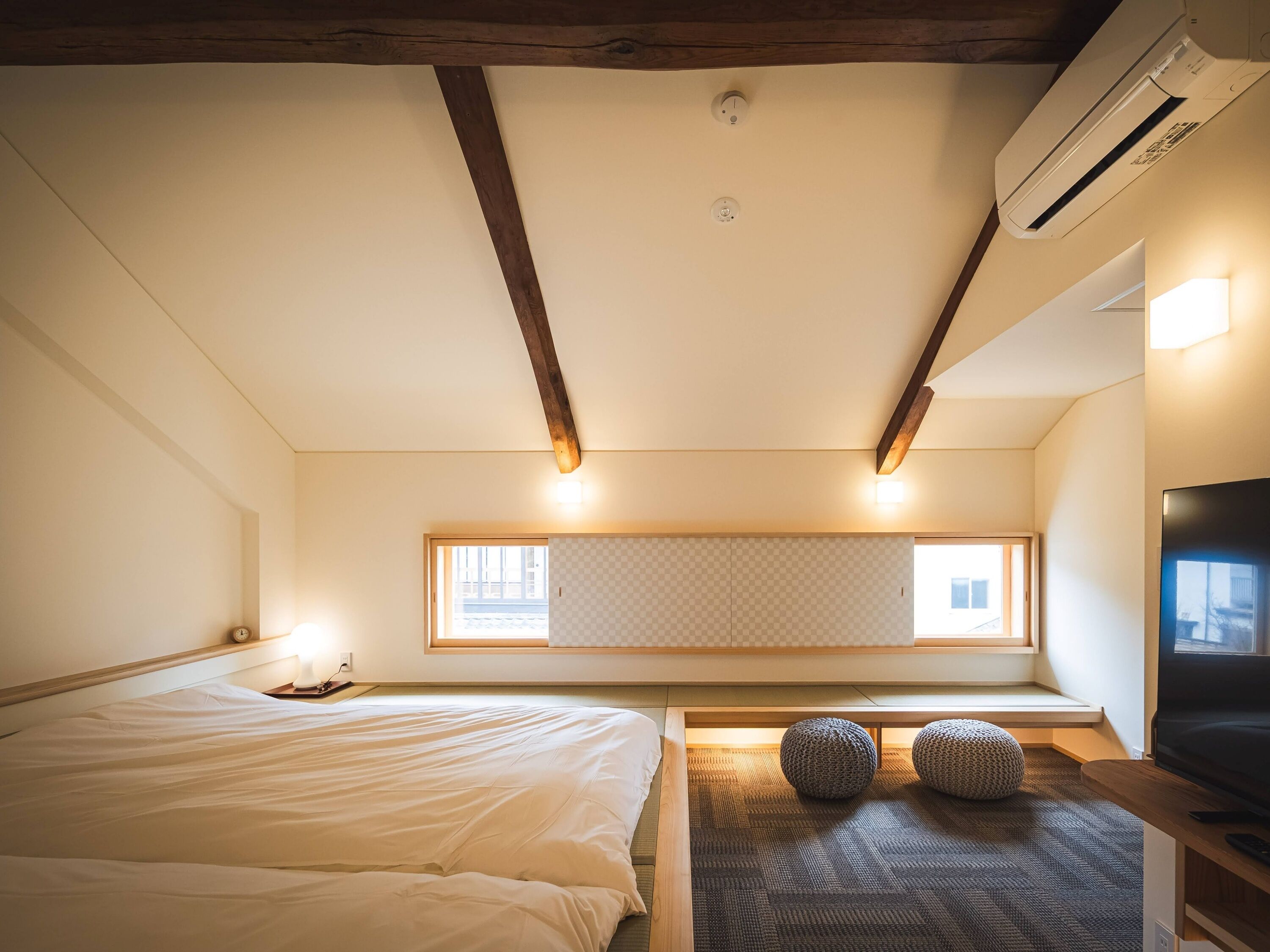 Un dormitorio con cama, televisor, ventana y ventilador de techo.