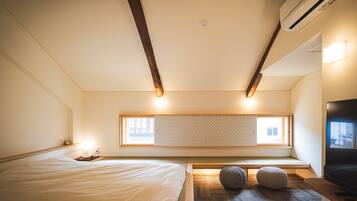 Un dormitorio con cama, televisor, ventana y ventilador de techo.