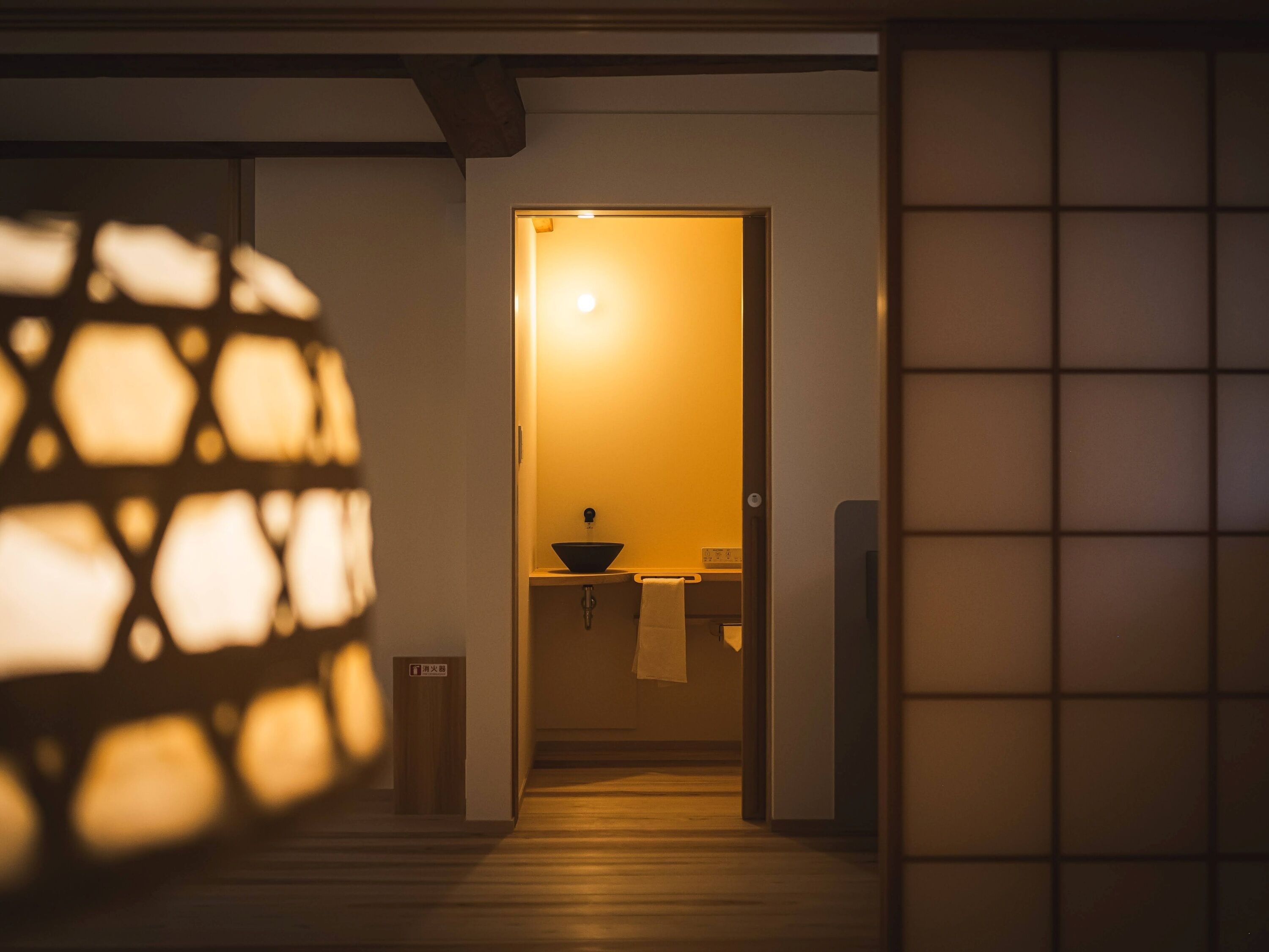 A hallway leading to a room with a sink and towel rack.