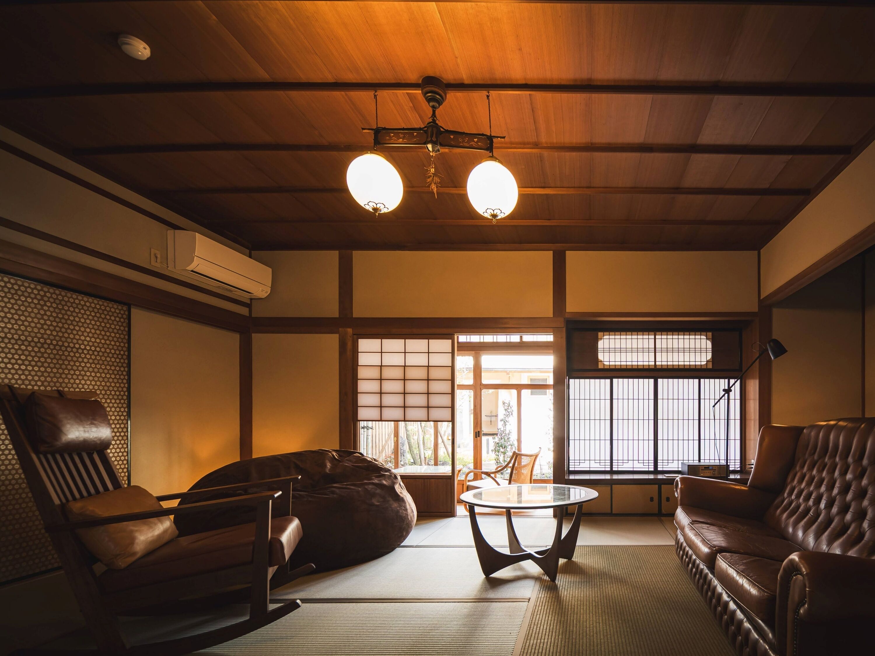 A traditional Japanese room with tatami flooring, a low wooden ceiling, and sliding shoji doors.