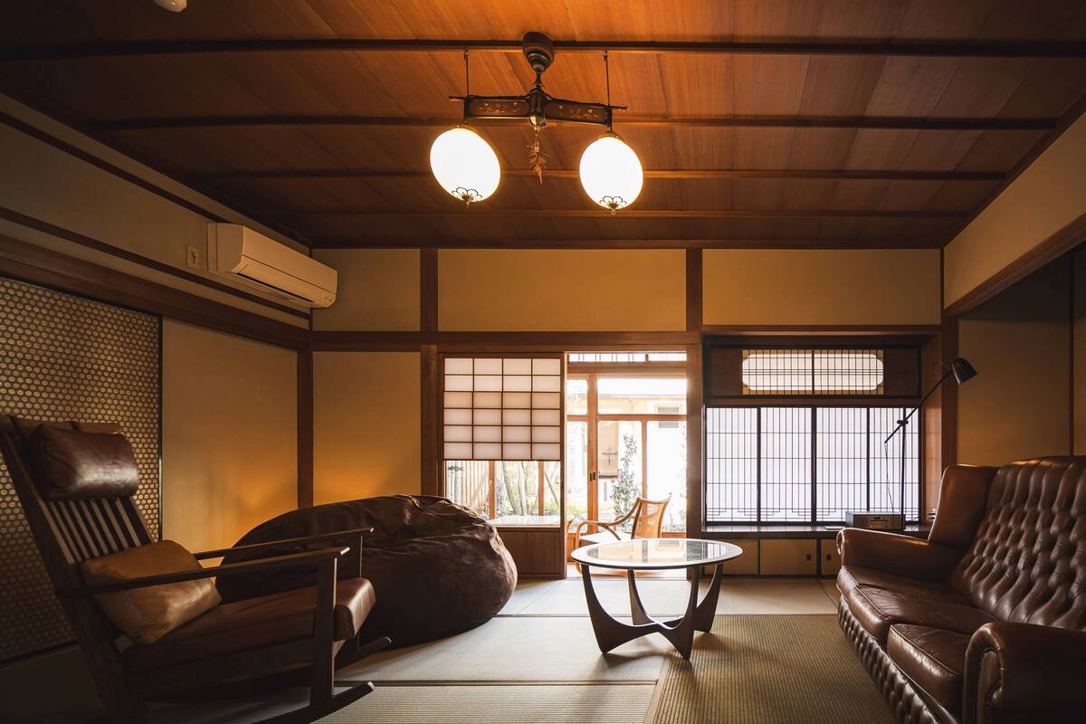 A traditional Japanese room with tatami flooring, a low wooden ceiling, and sliding shoji doors.