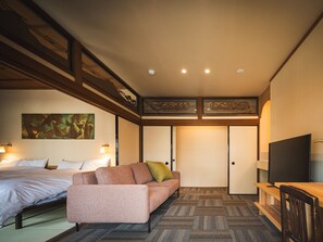 A hotel room with a bed, a sofa, a TV, and a wardrobe. - UCHIKO-Inn KURA (Uchiko)