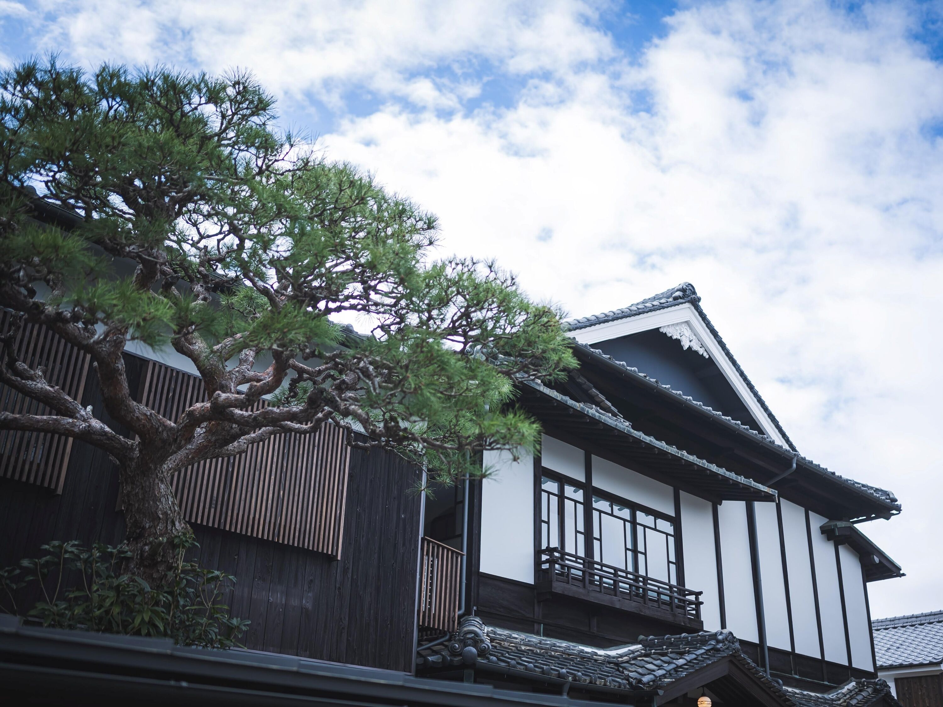 Il s’agit d’un bâtiment japonais traditionnel, doté d’une structure en bois, d’un toit recouvert de tuiles et d’un grand arbre qui se trouve devant.