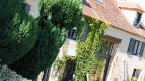 A building with a tiled roof, a visible window, and a door. - Le Champ Bagnolet (Voussac)
