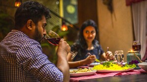 Une table à manger avec des assiettes remplies de nourriture, des verres de vin et une bougie.