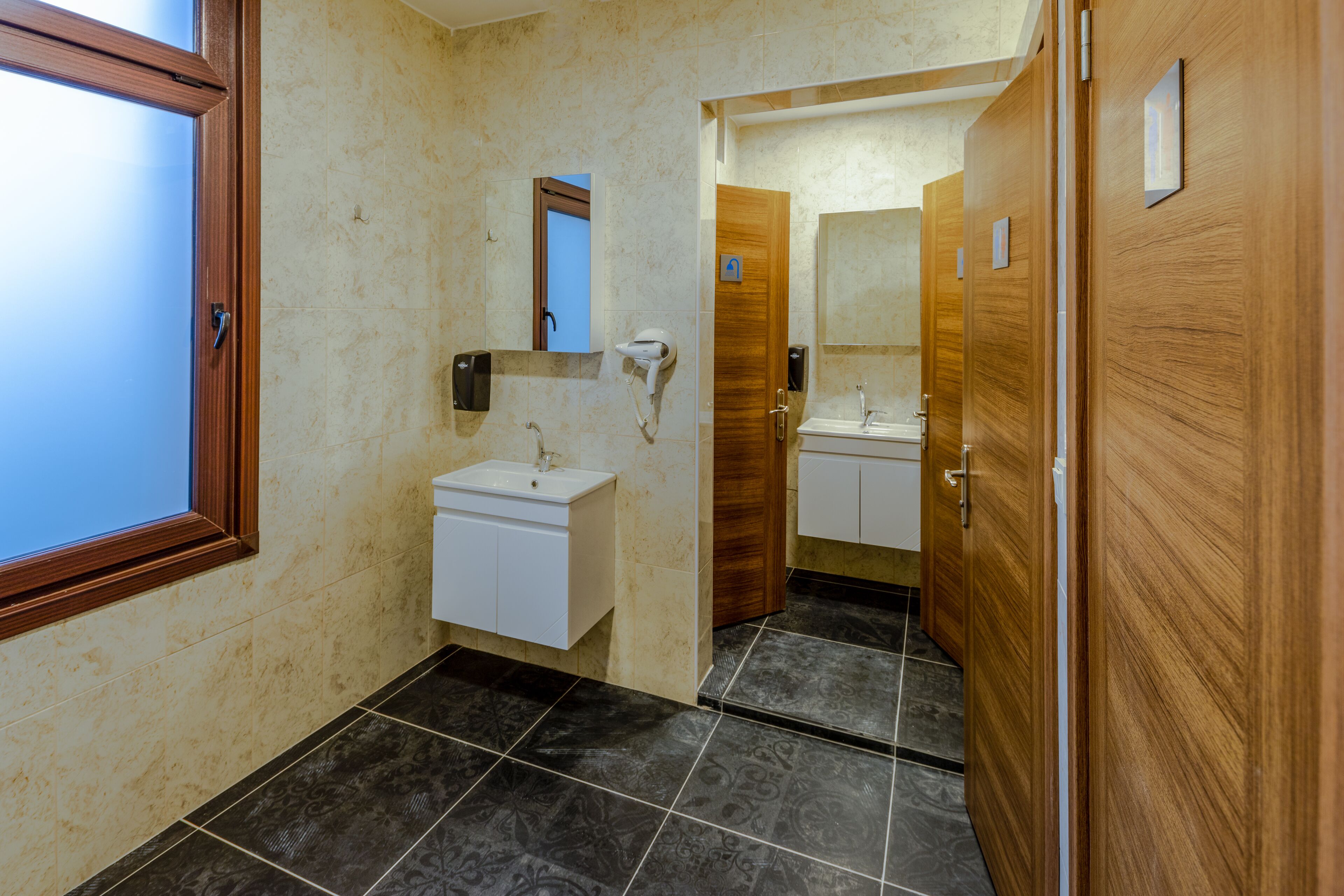 A bathroom with a wooden door, a sink, a mirror, and a towel rack.