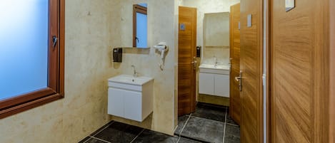 A bathroom with a wooden door, a sink, a mirror, and a towel rack.