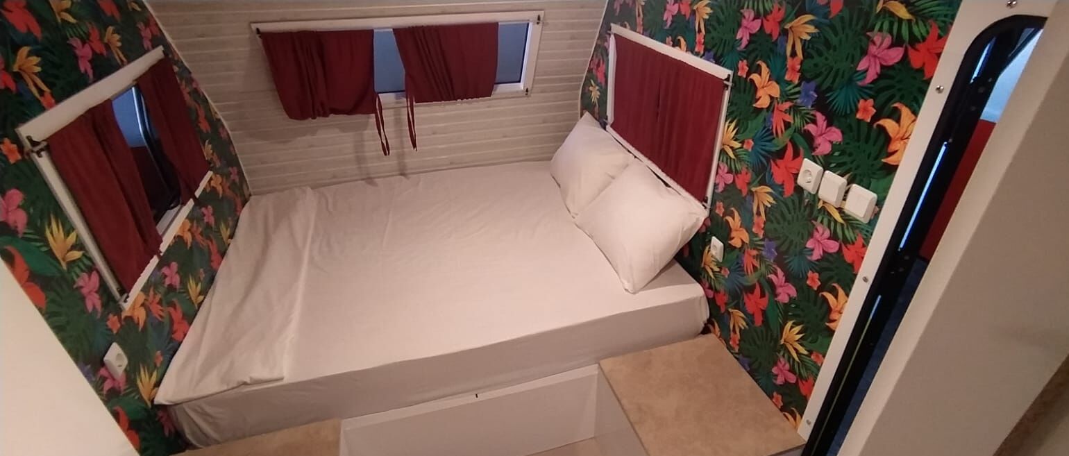 Pequeña habitación individual con cama, cortinas y ventana.