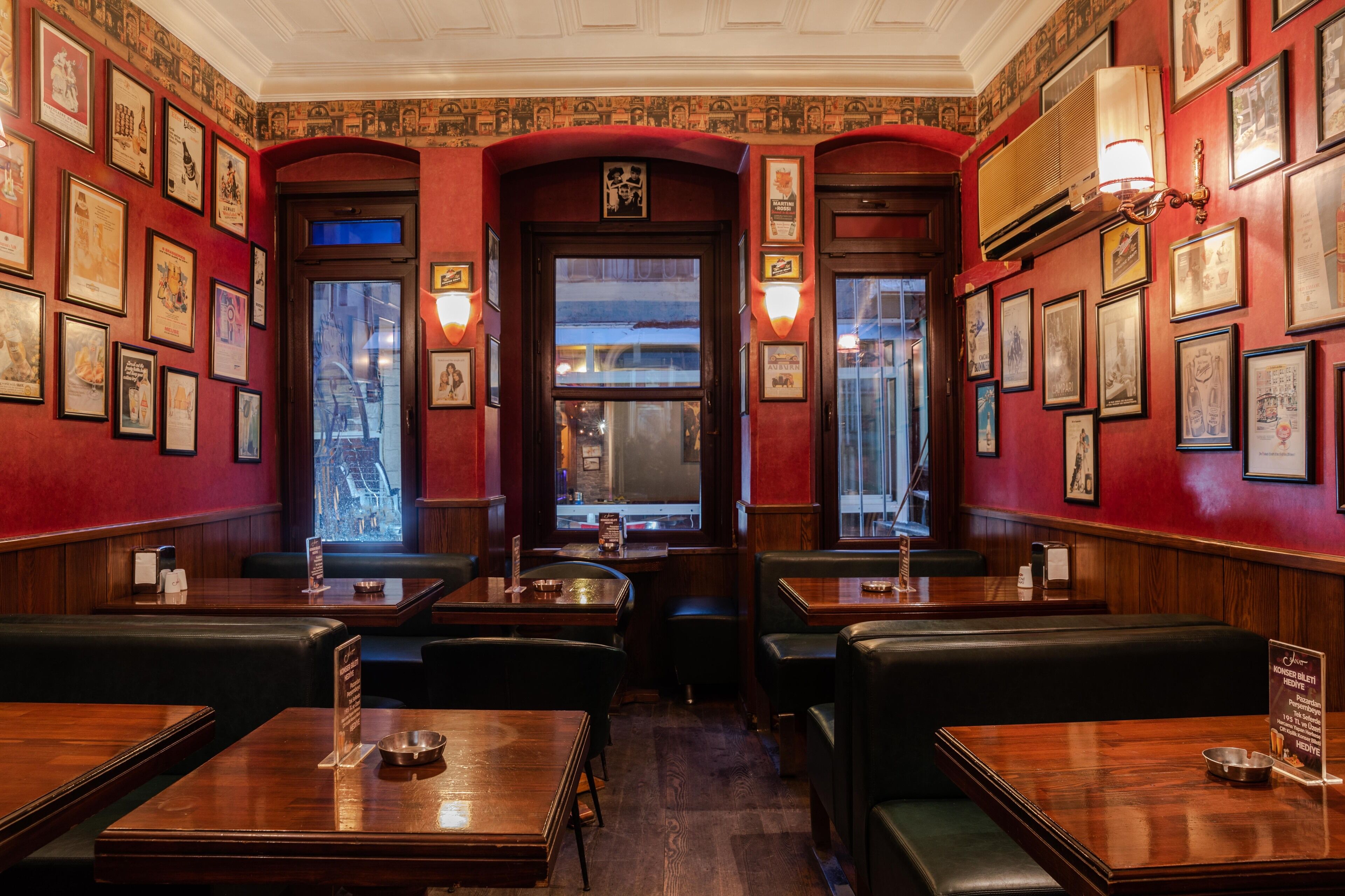 Un restaurant avec des banquettes et des tables, des tableaux encadrés aux murs et une grande fenêtre à l’arrière.