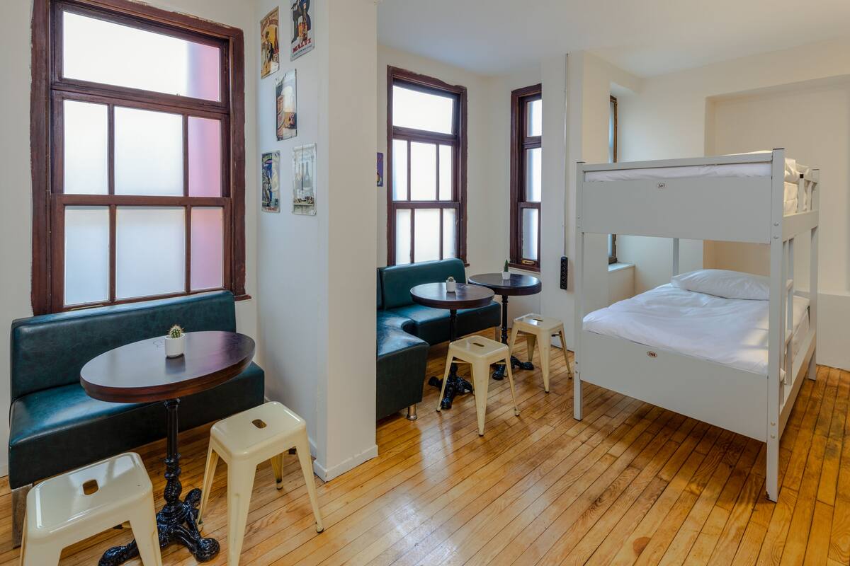Ein Zimmer mit einem Etagenbett, einer Schlafcouch, einem kleinen Tisch und einem Stuhl.